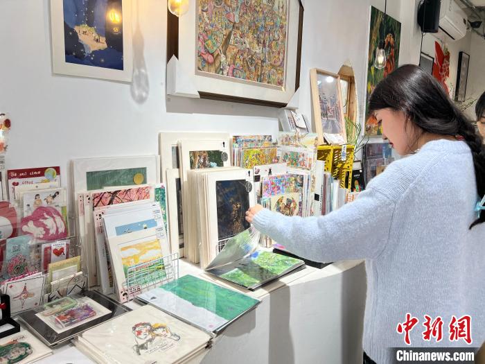 圖為藝術(shù)品商店內(nèi)，顧客挑選插畫作品?！＄婌?攝