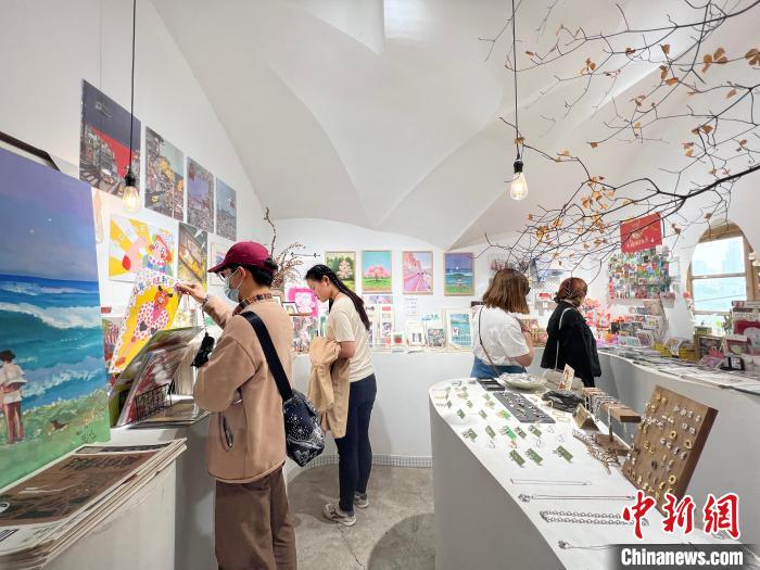 圖為藝術(shù)品商店內(nèi)，顧客挑選插畫作品?！＄婌?攝