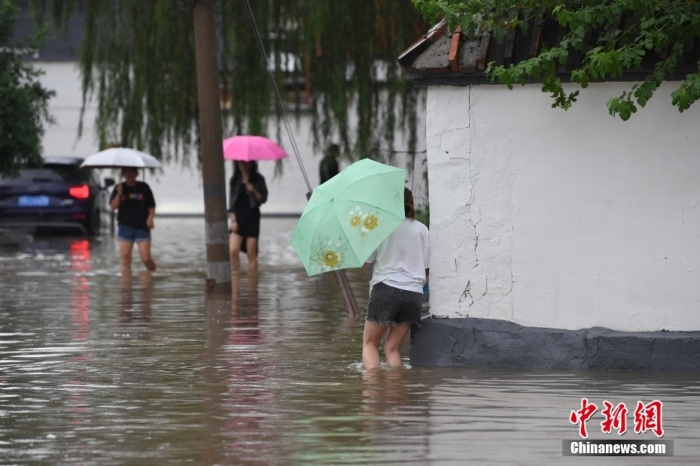 7月31日，市民行走在雨中的北京房山區(qū)瓦窯頭村。北京市氣象臺當(dāng)日10時發(fā)布分區(qū)域暴雨紅色預(yù)警信號。北京市水文總站發(fā)布洪水紅色預(yù)警，預(yù)計當(dāng)日12時至14時，房山區(qū)大石河流域?qū)⒊霈F(xiàn)紅色預(yù)警標(biāo)準(zhǔn)洪水。<a target='_blank' href='/'><p  align=