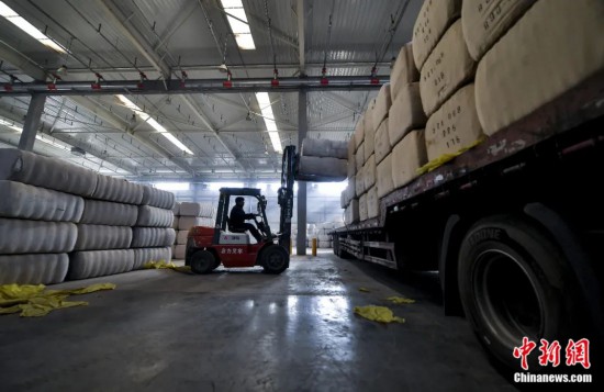 新疆喀什綜合保稅區(qū)，喀什啟路國際貿(mào)易有限公司的倉庫內(nèi)，工人正在裝載從塔吉克斯坦和烏茲別克斯坦進(jìn)口的棉花。劉新攝