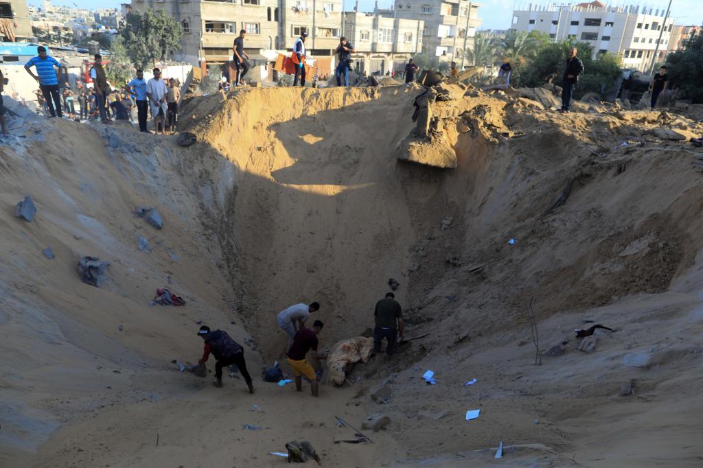 10月16日，在加沙地帶南部城市汗尤尼斯，人們?cè)谠庖陨幸u擊后的建筑廢墟中救援傷者。 新華社發(fā)（亞西爾·庫(kù)迪 攝）
