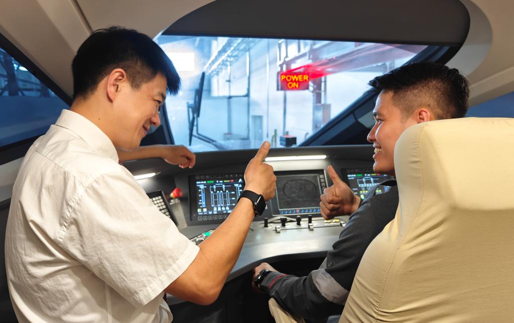 8月25日，在印度尼西亞萬隆的雅萬高鐵德卡魯爾動(dòng)車所內(nèi)，中國師傅穆振（左）在向印尼火車司機(jī)塞蒂亞萬講解動(dòng)車組出庫前的上電作業(yè)。