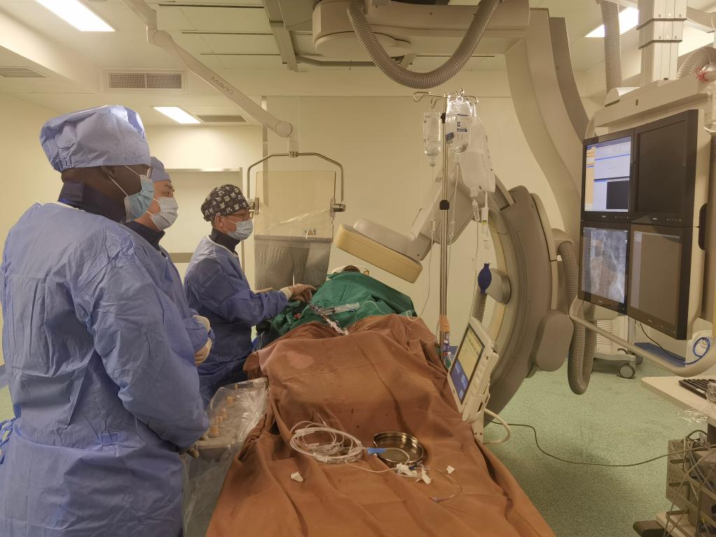 中國第29批援幾內(nèi)亞醫(yī)療隊隊員、首都醫(yī)科大學(xué)附屬北京天壇醫(yī)院心內(nèi)科副主任醫(yī)師王汝朋（右一）正在給患者做手術(shù)。（北京天壇醫(yī)院供圖）