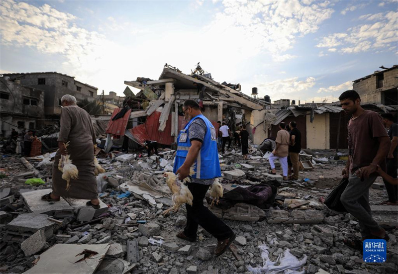 10月27日，在加沙地帶南部城市汗尤尼斯，人們經(jīng)過以軍襲擊后的房屋廢墟。