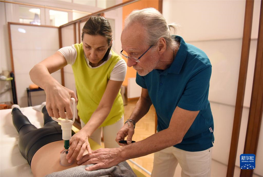 12月12日，在奧地利維也納，科格勒醫(yī)生（右）和助手在為病人進(jìn)行拔罐治療。新華社記者 賀燦鈴 攝