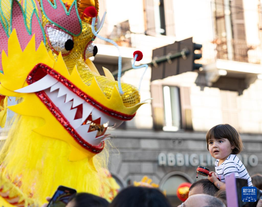2月18日，在意大利羅馬，一名小朋友在彩妝巡游上觀看舞龍。新華社記者 李京 攝