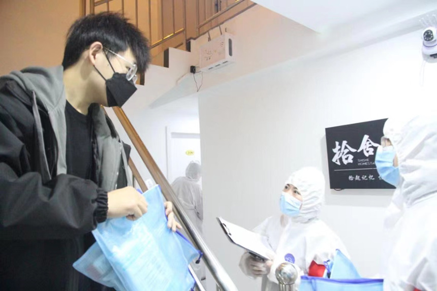 社區(qū)工作人員和志愿者身穿防護(hù)服上門送馬應(yīng)龍大健康防疫包。徐帥攝