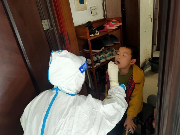 醫(yī)務(wù)工作者為封控區(qū)的居民上門采樣核酸。單位供圖