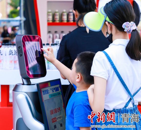 圖為一名小朋友正在和機器人“志愿者”進行互動。 沐聞 攝