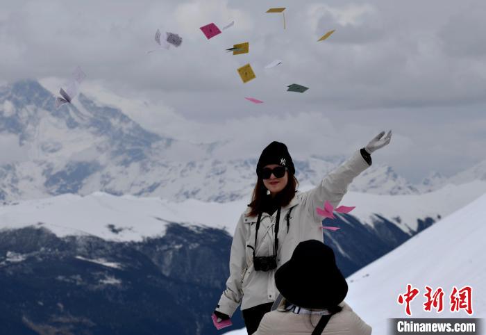 圖為5月14日，游客在西藏林芝色季拉山觀景臺拋灑“隆達”(風馬旗，藏族民眾的一種祈福方式)?！±盍?攝