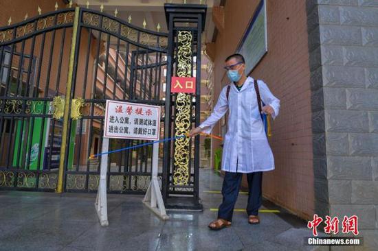 資料圖：?？诮?jīng)濟(jì)學(xué)院的工作人員在學(xué)生宿舍樓入口消毒。 中新社記者 駱云飛 攝