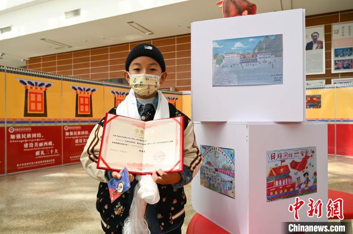 圖為一名獲獎學生與自己的繪畫作品合影?！≮w朗 攝