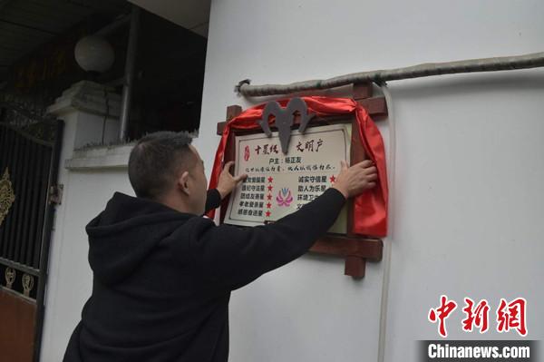 桂溪鎮(zhèn)渭溝村政府工作人員為“十星級(jí)文明戶”掛上牌匾。　楊勇 攝