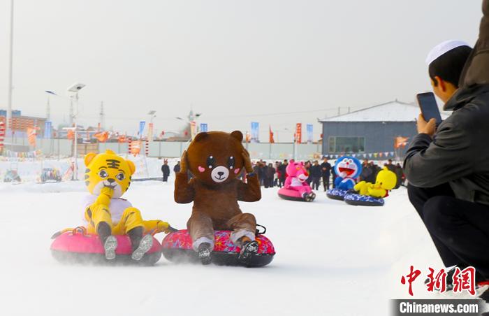 圖為臨夏市南龍鎮(zhèn)馬家莊村舉辦的鄉(xiāng)村文化旅游節(jié)上，游客穿著卡通服裝在體驗雪上飛碟項目。近年來，臨夏州形成了“春賞花、夏避暑、秋摘果、冬玩雪”的全季節(jié)旅游產(chǎn)品體系。(資料圖) 高展 攝