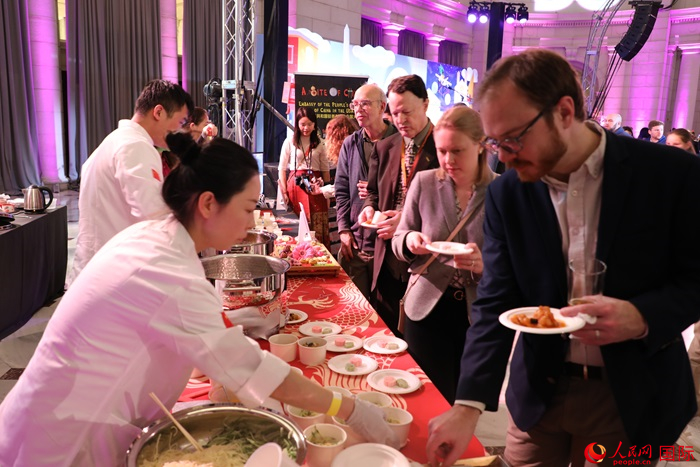 當(dāng)?shù)貢r間3月7日晚，華盛頓聯(lián)合車站廣場舉行駐美使團(tuán)“使館主廚挑戰(zhàn)賽”。圖為當(dāng)?shù)孛癖娫谥袊古_前體驗(yàn)中國美食。人民網(wǎng)記者 李志偉攝