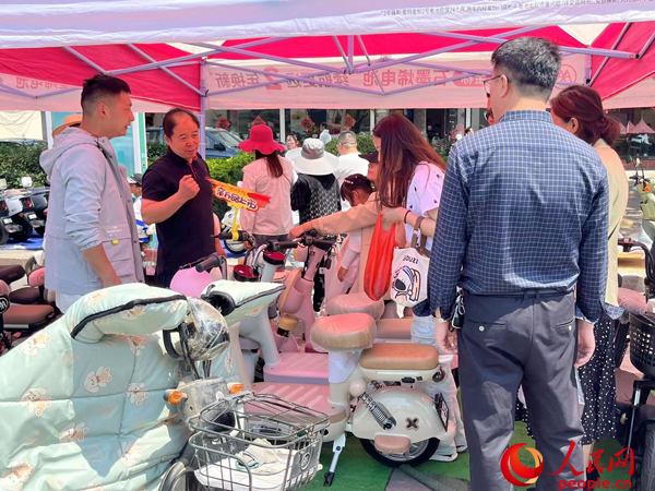 某電動自行車品牌工作人員向消費者介紹以舊換新相關(guān)情況。人民網(wǎng)記者 杜燕飛攝