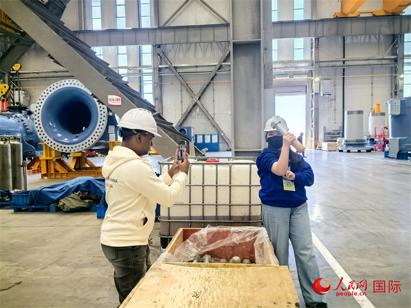 外媒記者掂量廠房內(nèi)的巨型螺栓。人民網(wǎng) 楊春燕攝