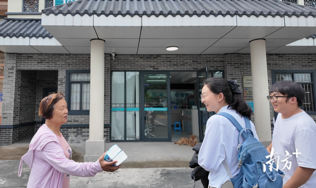 公共服務(wù)組成員王櫻潔（中）和張龍（右）在崖口村衛(wèi)生室前跟村民打招呼。