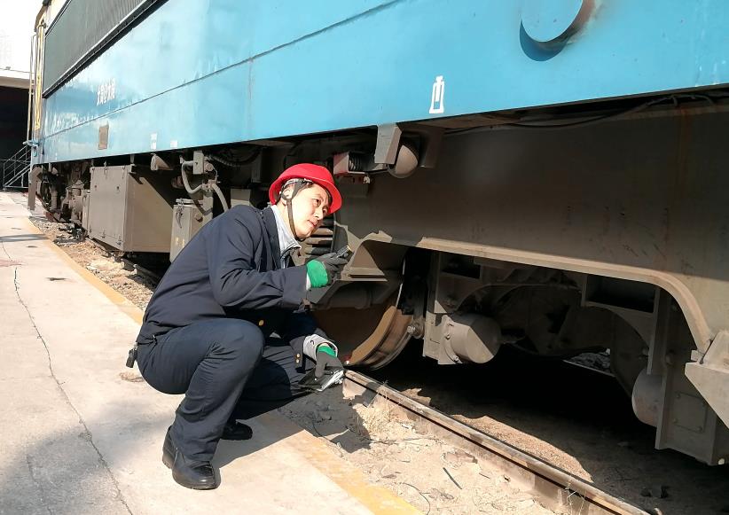 韓文盛全神貫注檢查機(jī)車走行部。