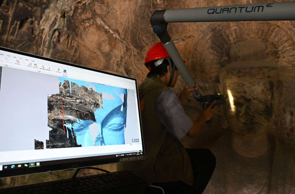 2025年4月9日，武漢大學(xué)文化遺產(chǎn)智能計(jì)算實(shí)驗(yàn)室團(tuán)隊(duì)成員在魏字洞使用關(guān)節(jié)臂掃描儀對(duì)佛像進(jìn)行數(shù)字化掃描。圖片來(lái)源新華社