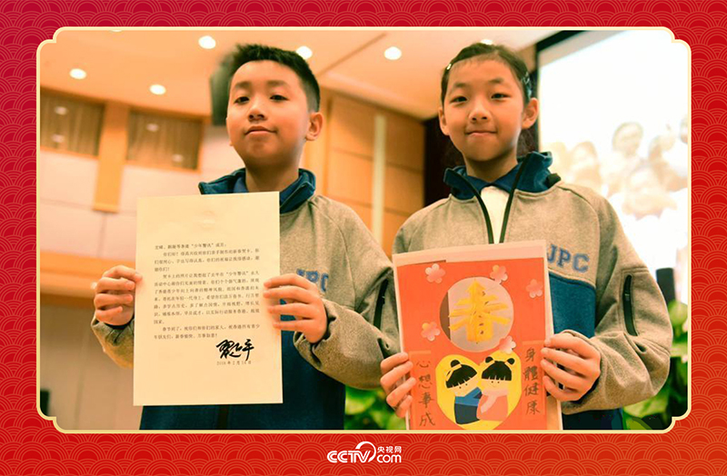 圖為香港“少年警訊”成員郭宏晞（左）展示習主席回信、羅顥凝（右）展示送給習主席的賀卡并合影。
