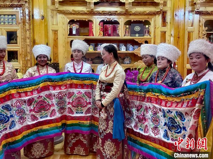 圖為女性展示村民自發(fā)繡制的“百米五彩哈達”?！±钣穹?攝