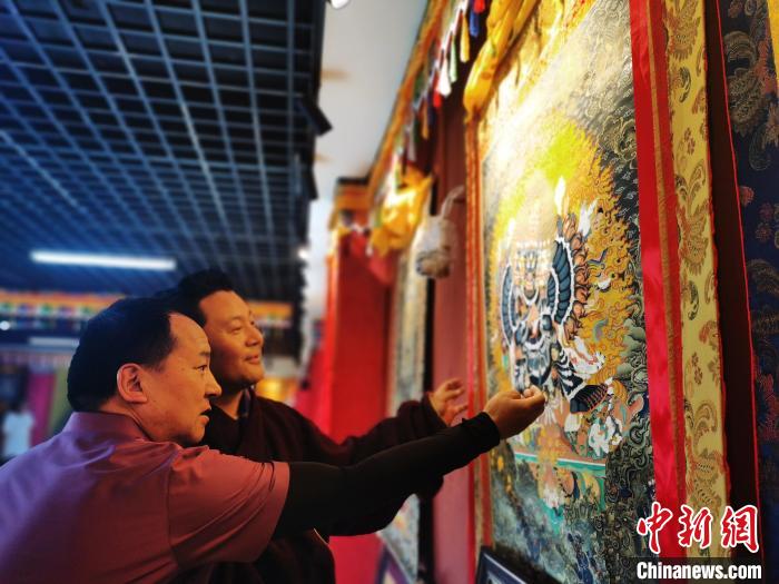 圖為久美尖措展示唐卡作品?！?zhí)砀?攝