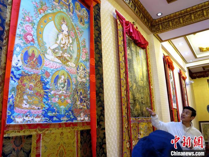 圖為完德尖措展示熱貢龍樹(shù)畫(huà)苑內(nèi)的唐卡。　張?zhí)砀?攝