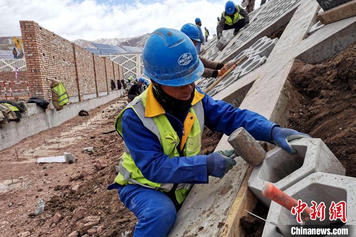 圖為光伏發(fā)電項目施工區(qū)工人在護坡鋪設(shè)空心磚?！±铍h 攝