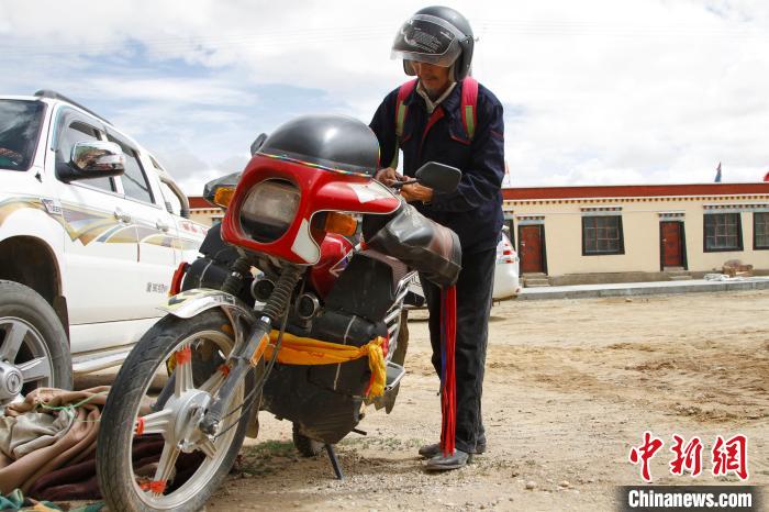 圖為白瑪準(zhǔn)備騎摩托車(chē)巡湖?！≮w朗 攝