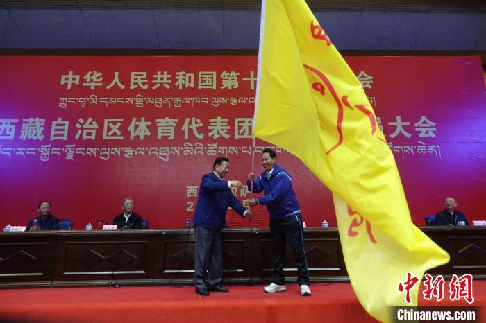 西藏自治區(qū)副主席甲熱·洛桑丹增授代表團團旗，西藏自治區(qū)體育局局長尼瑪次仁接旗?！∪轿木?攝