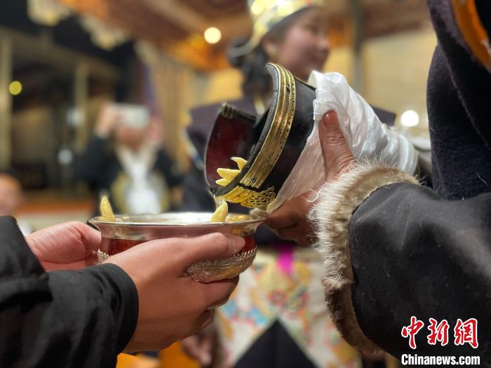 圖為主人在碗中斟滿青稞酒?！∪轿木?攝