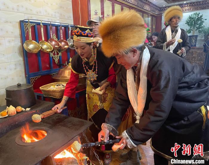 圖為人們在火上烤節(jié)日美食“結(jié)達”?！∪轿木?攝