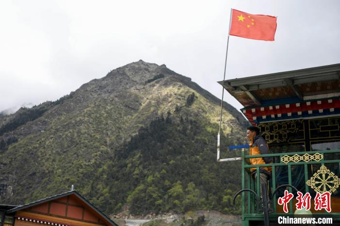 村民站在樓房上觀望?！钊A峰 攝