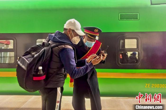 圖為日喀則火車站工作人員服務(wù)乘客?！《飞降?攝