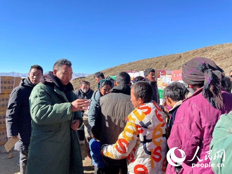 定日縣公安局干警頓珠次仁（左二）正在協(xié)助分發(fā)物資。人民網(wǎng)記者 郝潔攝