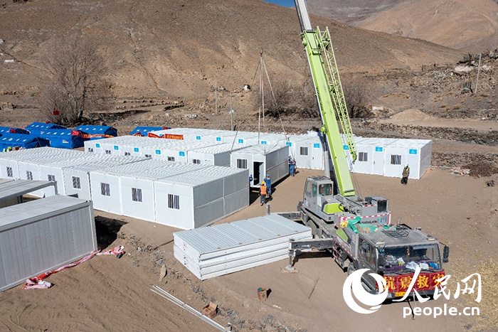 1月9日，在日喀則市定日縣長所鄉(xiāng)古榮村安置點，救援人員和施工人員合力抓緊搭建移動板房，確保受災群眾溫暖過冬。人民網(wǎng)記者 翁奇羽攝