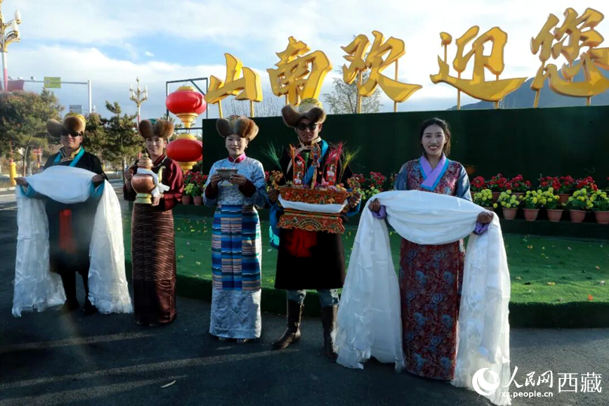 扎西曲登社區(qū)的居民在“山南歡迎您”標(biāo)志前，手持潔白哈達(dá)和切瑪，列隊(duì)迎接來自區(qū)內(nèi)外的游客，用最隆重的禮儀開啟一場(chǎng)沉浸式藏歷新年民俗體驗(yàn)之旅。人民網(wǎng)記者 吳雨仁攝