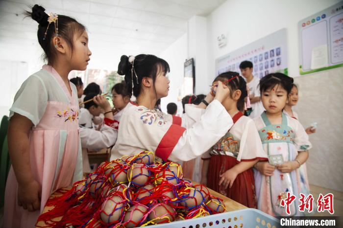 圖為幼兒園的老師們穿上漢服為小朋友們戴上彩蛋，寓意著幸福安康?！《^生 攝